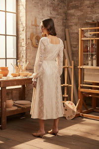 Woman wearing a cream lace jacquard maxi dress with square neckline