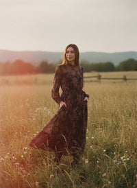 Woman in dark floral bohemia maxi dress with pockets standing in a field