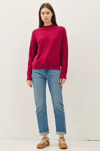 Woman wearing a highneck basic cropped sweater with light blue cuffed jeans and sneakers