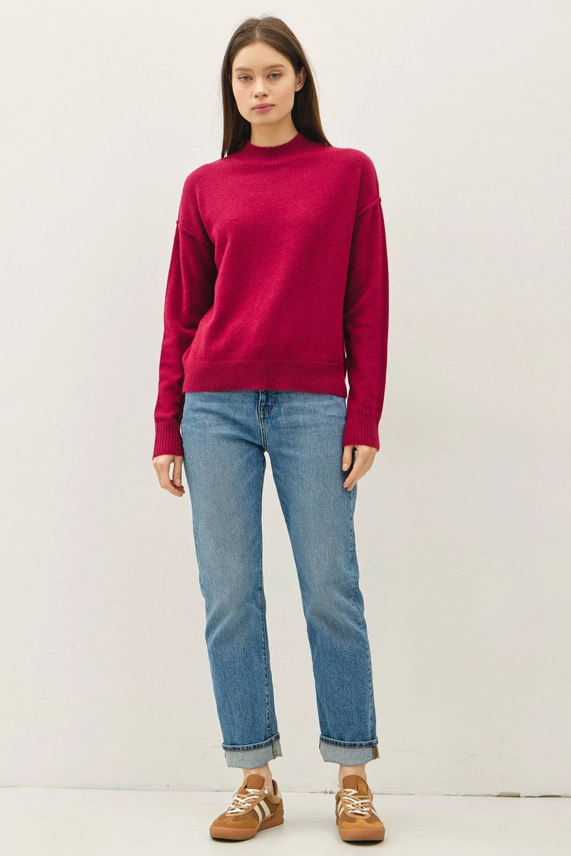 Woman wearing a highneck basic cropped sweater with light blue cuffed jeans and sneakers
