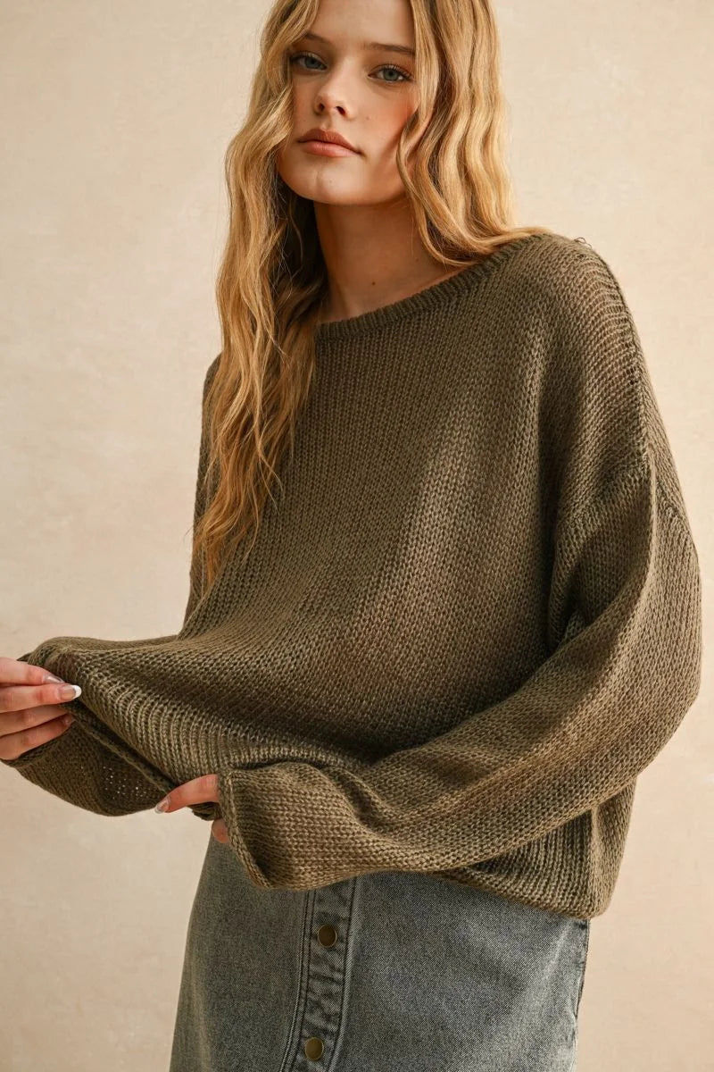 Woman wearing a light weight long olive green knit sweater and denim skirt