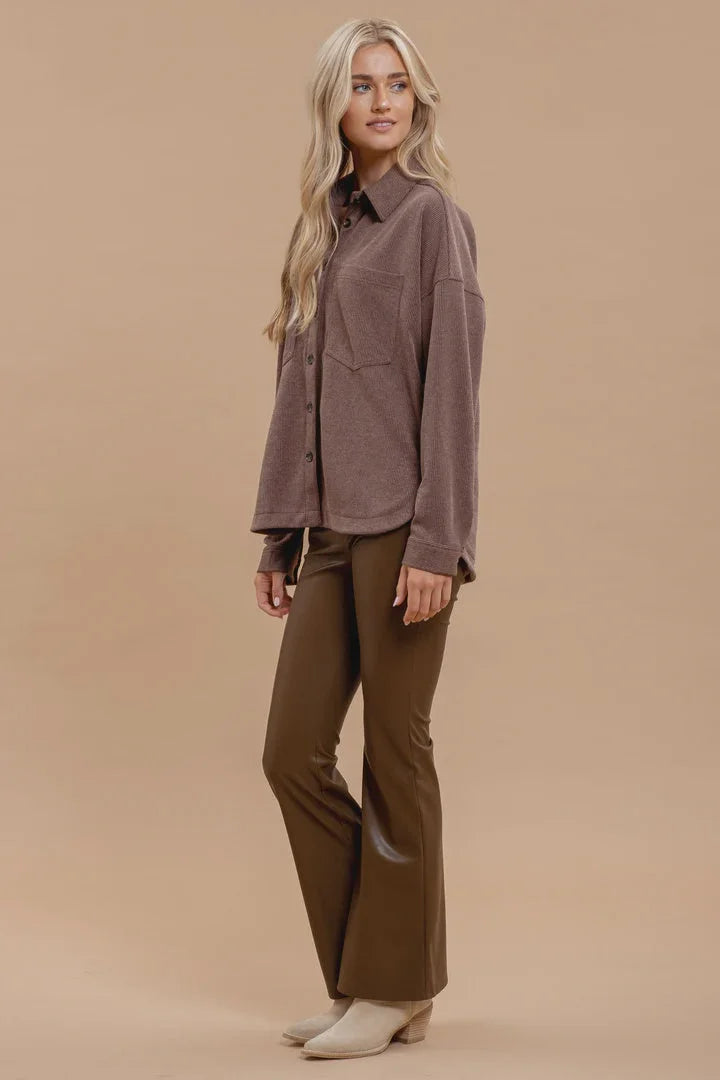 Woman in mauve oversized pinstripe button shirt and brown flared pants