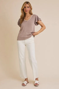 Woman wearing an elegant v-neck top with neck lace trim and ruffle sleeves