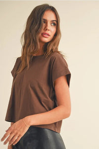 Woman modeling a round neck cuffed short-sleeved top with a black leather skirt