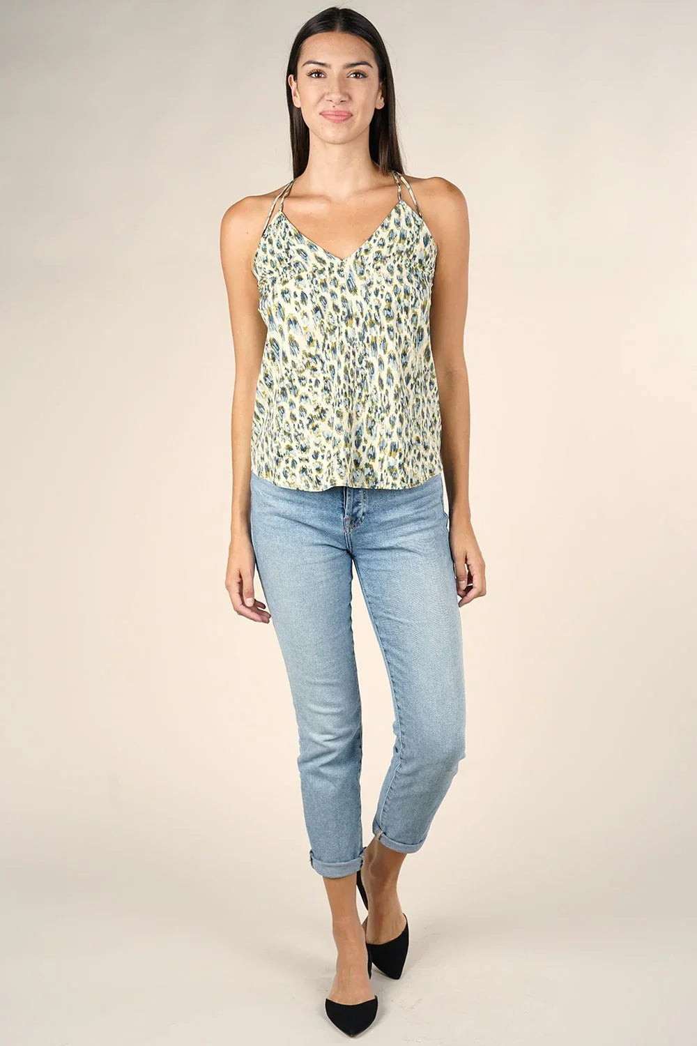 Woman wearing light blue cropped jeans and pale green animal print spaghetti strap tank