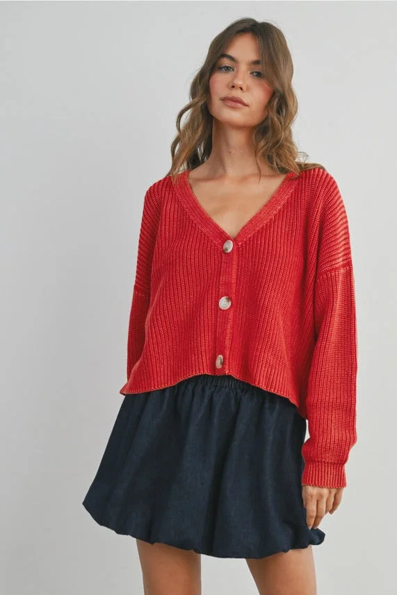 Woman modeling red V-neck buttoned ribbed long sleeve cardigan over dark mini skirt