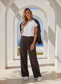 Woman modeling white T-shirt with dark brown supply walker pants and sneakers