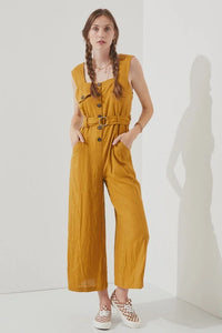 Woman wearing a sleeveless square neck button down ankle jumpsuit in mustard color