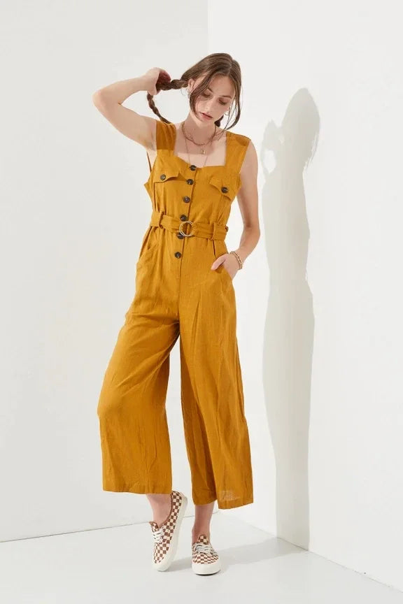 Woman wearing a sleeveless square neck button down ankle jumpsuit in mustard color