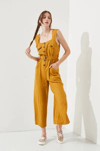 Woman wearing a sleeveless square neck button down ankle jumpsuit in mustard color