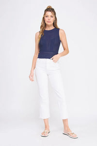 Woman wearing a navy blue mixed pointelle fine gauge tank top and white cropped jeans
