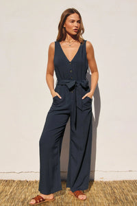 Woman in navy BUTTON DOWN SASH BELT JUMPSUIT featuring v-neck and button closures