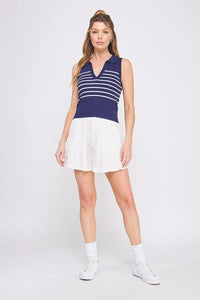 Woman wearing a navy and white striped knit sleeveless polo tank top and white skirt