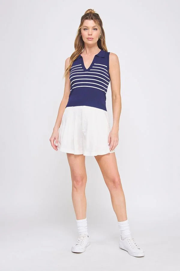 Woman wearing a navy and white striped knit sleeveless polo tank top and white skirt