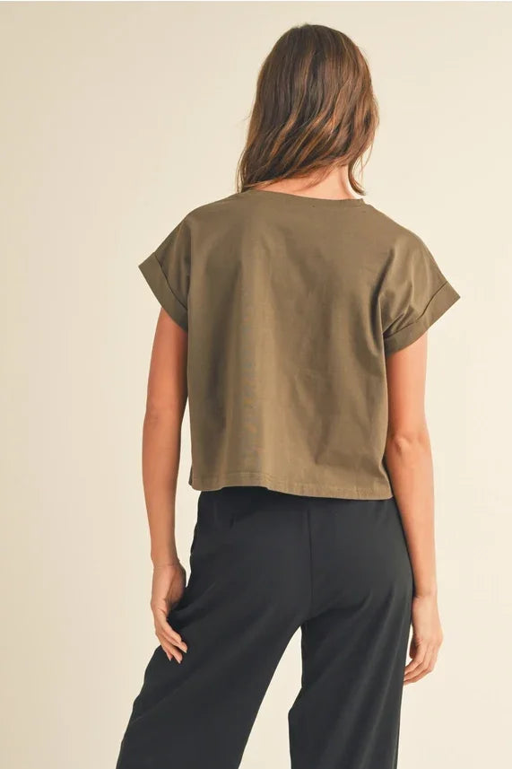 Woman wearing olive green round neck cuffed sleeve top with black wide-leg pants