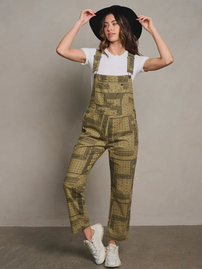 Woman in olive green patterned overalls and black hat showcasing women’s boho chic clothing