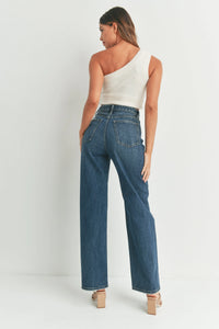 Woman in one-shoulder white top and blue high waisted skater jean, viewed from behind