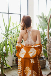 Woman wearing an orange tie dye dress with a seamless lace racerback bralette