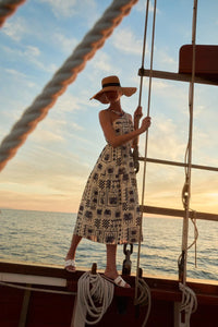 Woman in a halter neck abstract print dress and sun hat on a boat