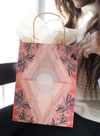 Woman holding a LOVE ALL WAYS Gift Bag in pink and black design