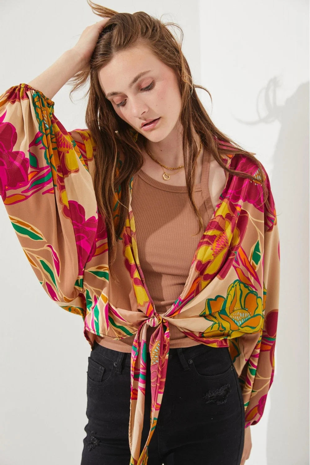 Woman in a pink blouse and black jeans showcasing a Floral Print Tie-Front Cardigan