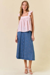 Woman in pink top and blue skirt wearing striped ruffle cap sleeved boho chic clothing in Shop Daisy product