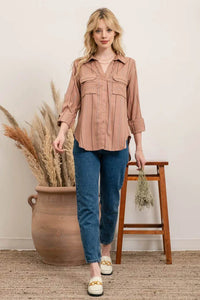 Woman in a pink multi striped button-up shirt and blue jeans, showcasing style