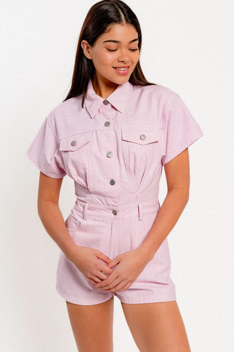 Woman in a pink shirt and shorts modeling a stylish short sleeve denim romper