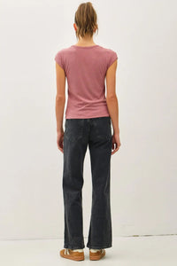 Woman wearing a pink ribbed cap sleeve T shirt paired with dark jeans