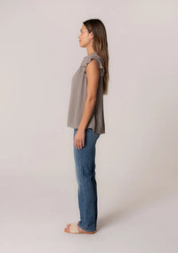 Woman in profile wearing a flowy gray crinkle gauze top and blue jeans