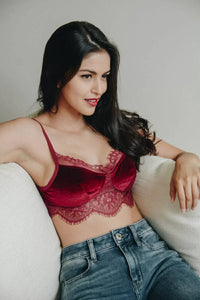 Woman wearing a red lace boho half cami while sitting on a couch