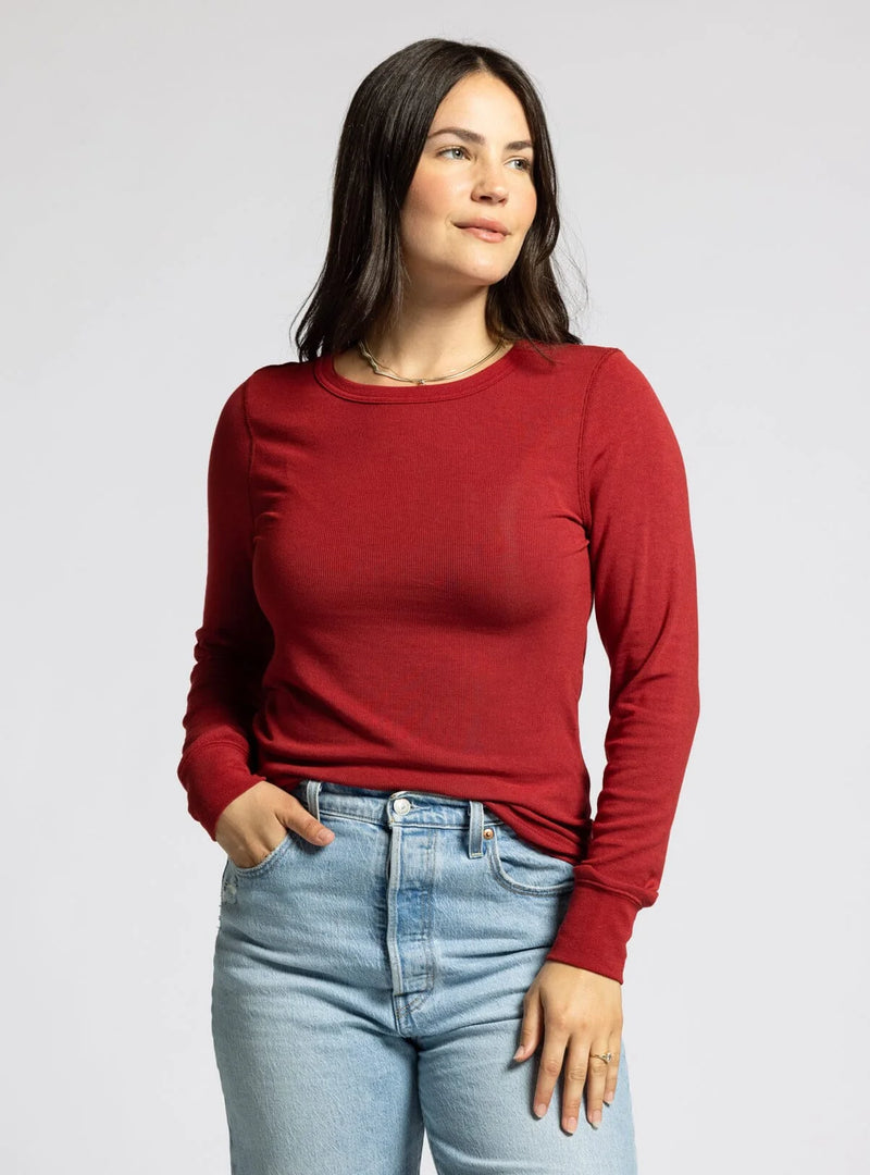 Woman in a red long sleeve top and light blue jeans, showcasing women’s boho chic clothing