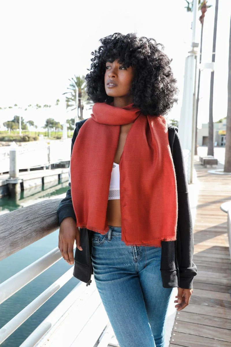 Woman stylishly wearing a Soft Woven Frayed Edge Scarf with jeans and a red scarf