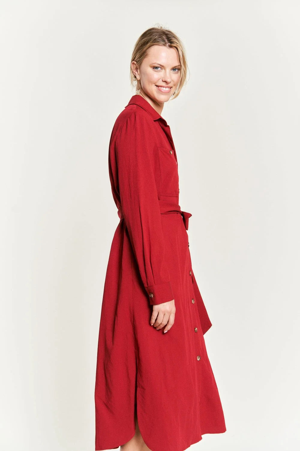 Woman in a red trench coat wearing a solid button belted long dress