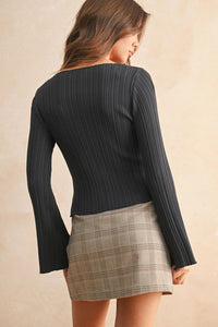 Woman wearing a ribbed long sleeve knitted top and plaid mini skirt for stylish casual wear