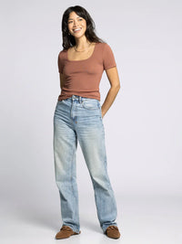 Woman modeling Supply Katara Tee with rust-colored top and light wash baggy jeans