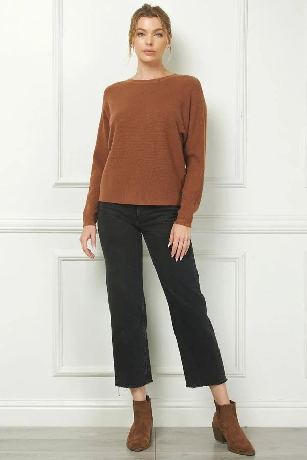 Woman in a rust-colored fine gauge mini waffle texture sweater and dark cropped pants