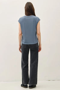 Woman wearing a blue bamboo cap sleeve basic round neck top and black wide-leg jeans