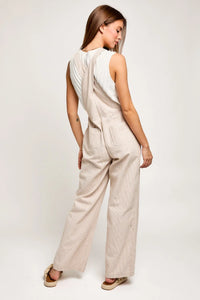 Woman in a sleeveless beige wide leg stripe jumpsuit, showcasing a flowy boho style