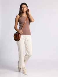 Woman in a sleeveless brown top and white pants showcasing the Edlin Basic Tank