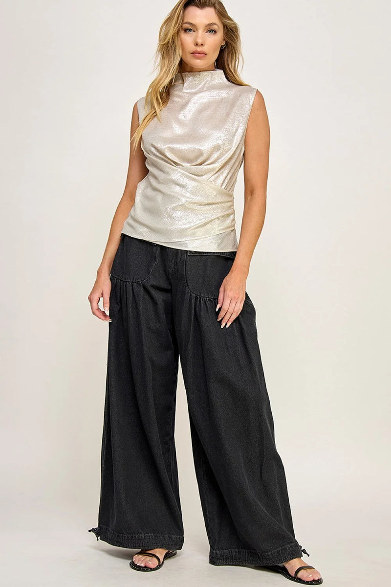 Woman in draped satin effect top paired with wide-leg black pants for a chic look