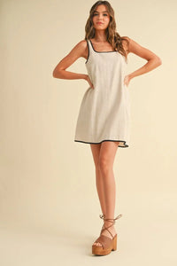 Woman in cream sleeveless dress with black trim and platform sandals, women’s boho chic clothing