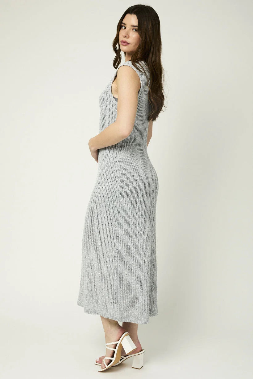 Woman in a sleeveless gray knit maxi dress posing sideways in a flowy boho style