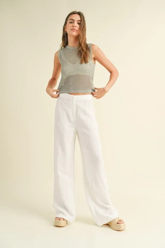 Woman in a crochet knitted sleeveless top and white wide-leg pants fashion outfit