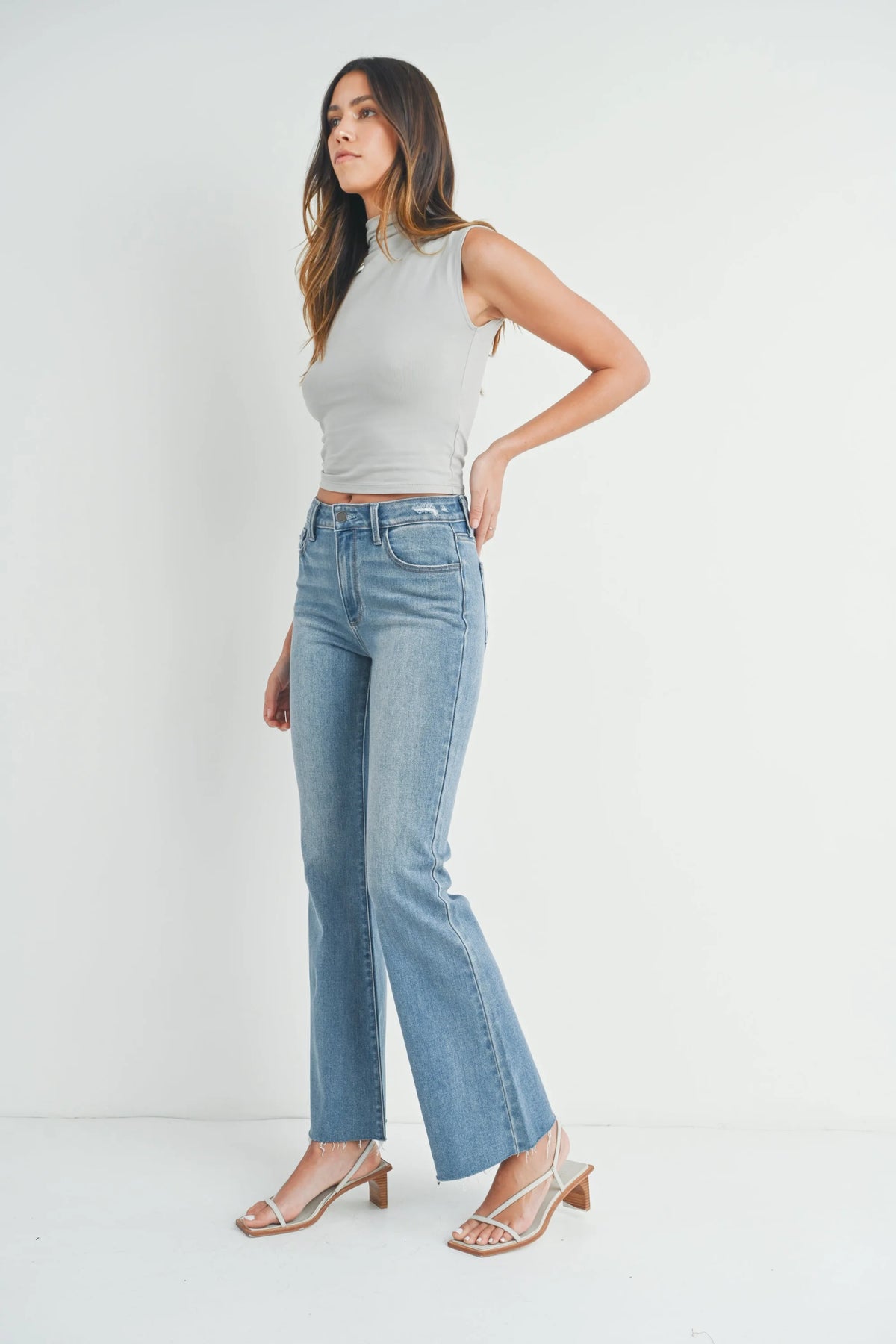 Woman in sleeveless gray top and light blue jeans, embodying boho free spirit style