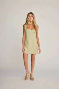 Woman in a sleeveless light green mini dress showcasing Sunday Ritual Dahlia Linen Dress
