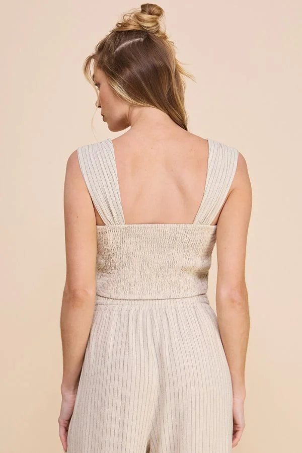 Woman in a sleeveless white jumpsuit showcasing the pinstriped soft linen cropped bustier tank