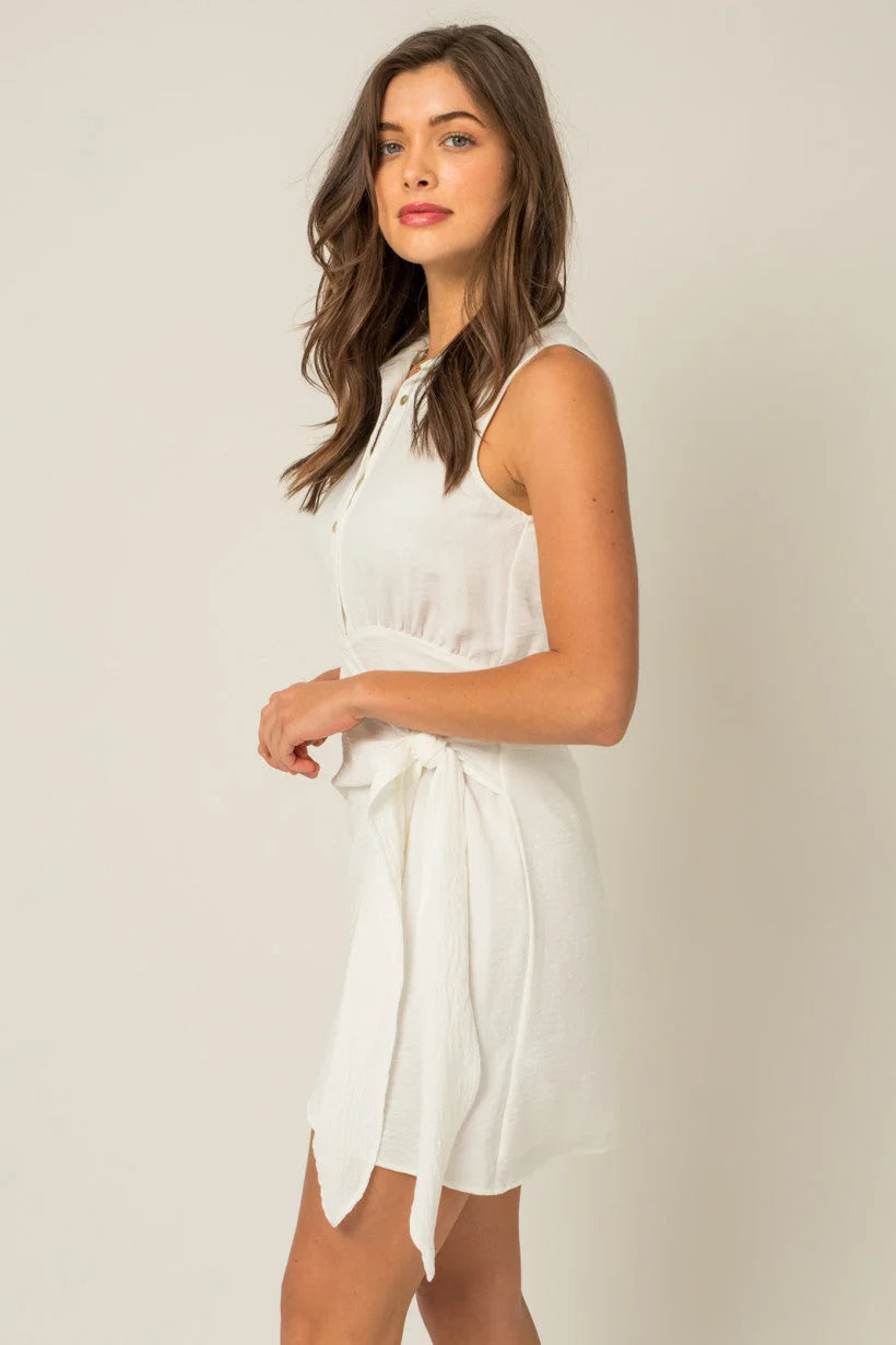 Woman in a flowy sleeveless white dress with tied waist, perfect for free spirit boho style