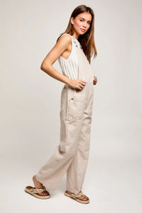 Woman in a sleeveless white top and beige wide leg pants showcasing a boho style