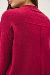Woman wearing a bright red highneck basic cropped sweater with visible seams